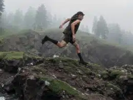 Homem a correr em montanha com neblina.