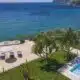 Vista de jardim com piscina e mar ao fundo.