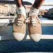 Sapatos bege sobre ponte com rio ao fundo.