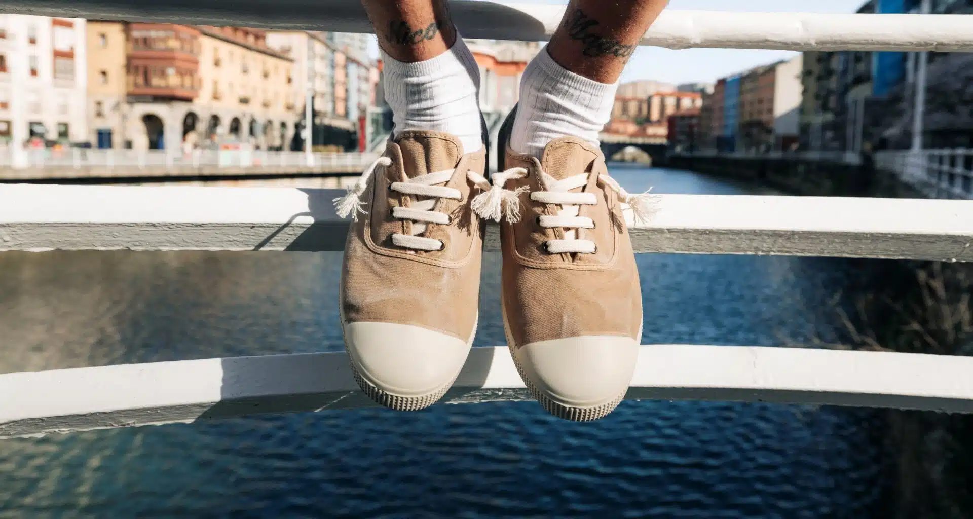 Sapatos bege sobre ponte com rio ao fundo.