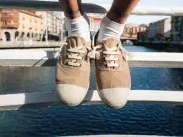 Sapatos bege sobre ponte com rio ao fundo.