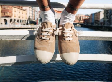 Sapatos bege sobre ponte com rio ao fundo.