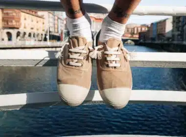 Sapatos bege sobre ponte com rio ao fundo.