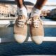 Sapatos bege sobre ponte com rio ao fundo.