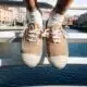 Sapatos bege sobre ponte com rio ao fundo.