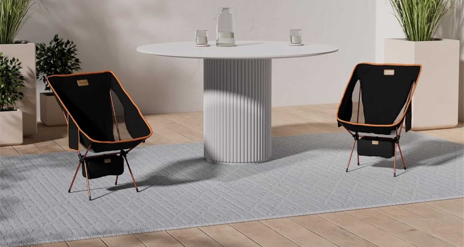 Sala com mesa redonda e duas cadeiras pretas.