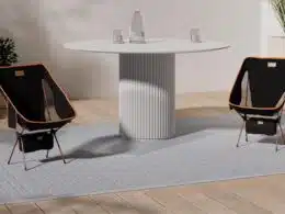Sala com mesa redonda e duas cadeiras pretas.