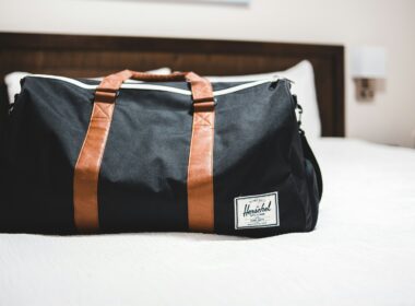 Saco de viagem preto em cima da cama.