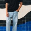 Homem com roupa casual frente a azulejos artísticos.