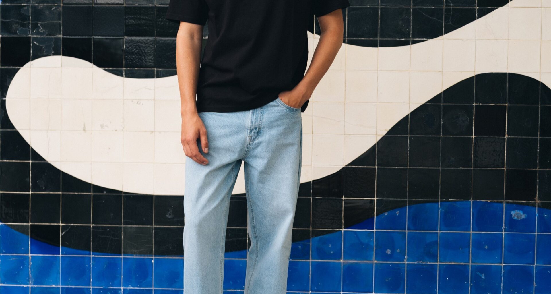 Homem com roupa casual frente a azulejos artísticos.
