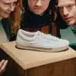 Pessoas observam ténis As novas sapatilhas Vans Skate Era Stub by Dime branco em pedestal.