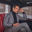 Homem elegante sentado numa viatura clássica.