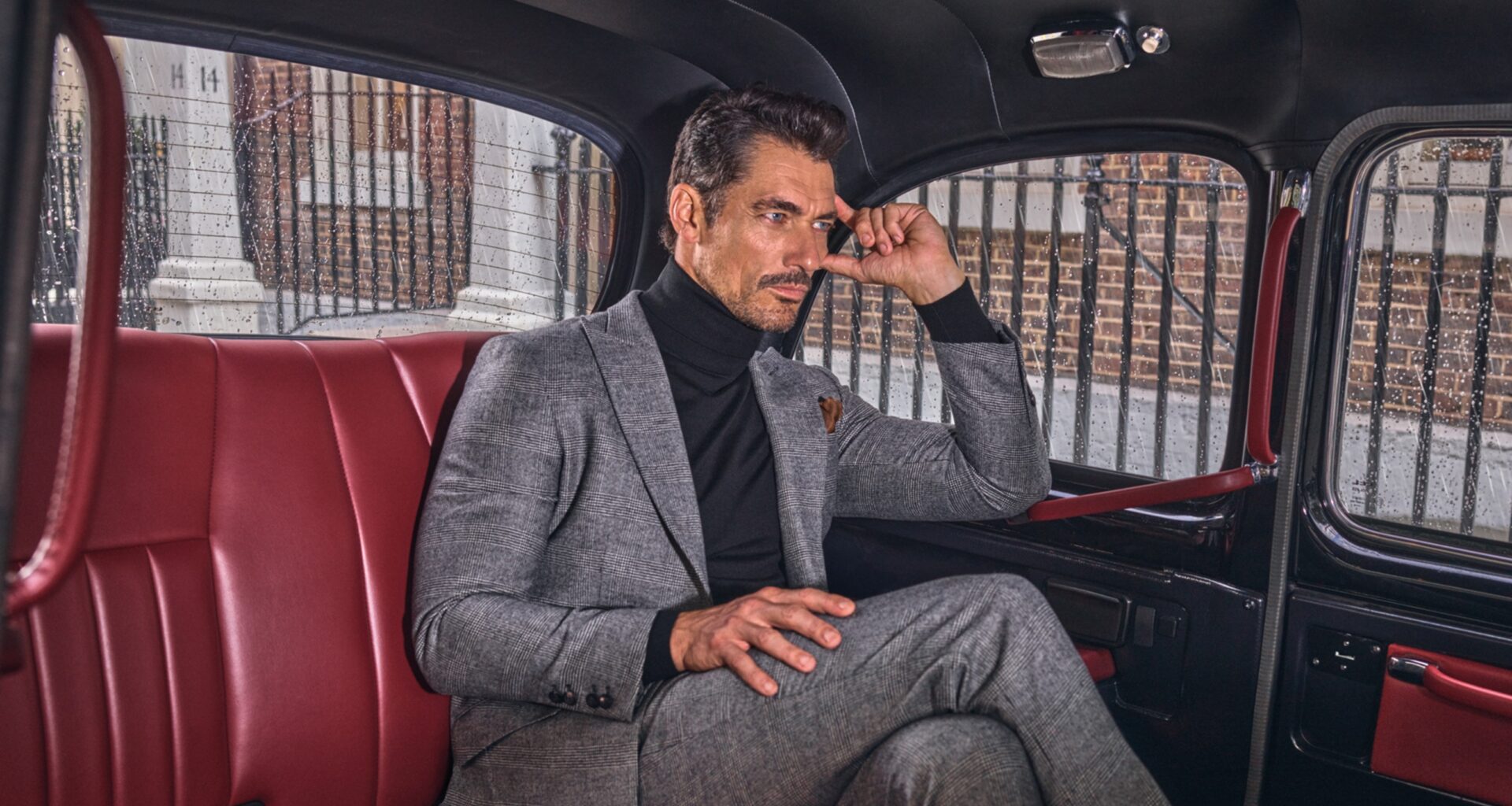 Homem elegante sentado numa viatura clássica.
