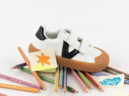 Sapatilha infantil sobre lápis de cor e desenhos.