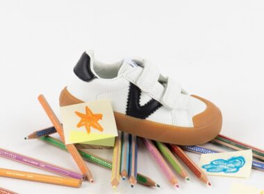 Sapatilha infantil sobre lápis de cor e desenhos.