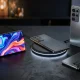 Vários smartphones cinzentos sobre uma mesa com carregador sem fios.