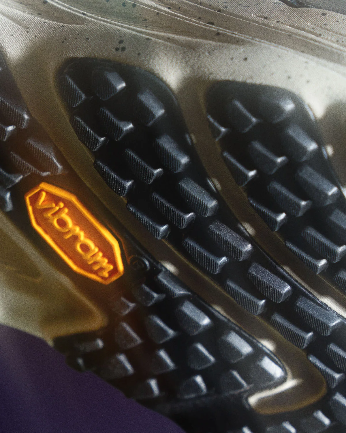 Detalhe da sola das sapatilhas de trail Merrell homem com relevos pretos profundos e logótipo amarelo Vibram