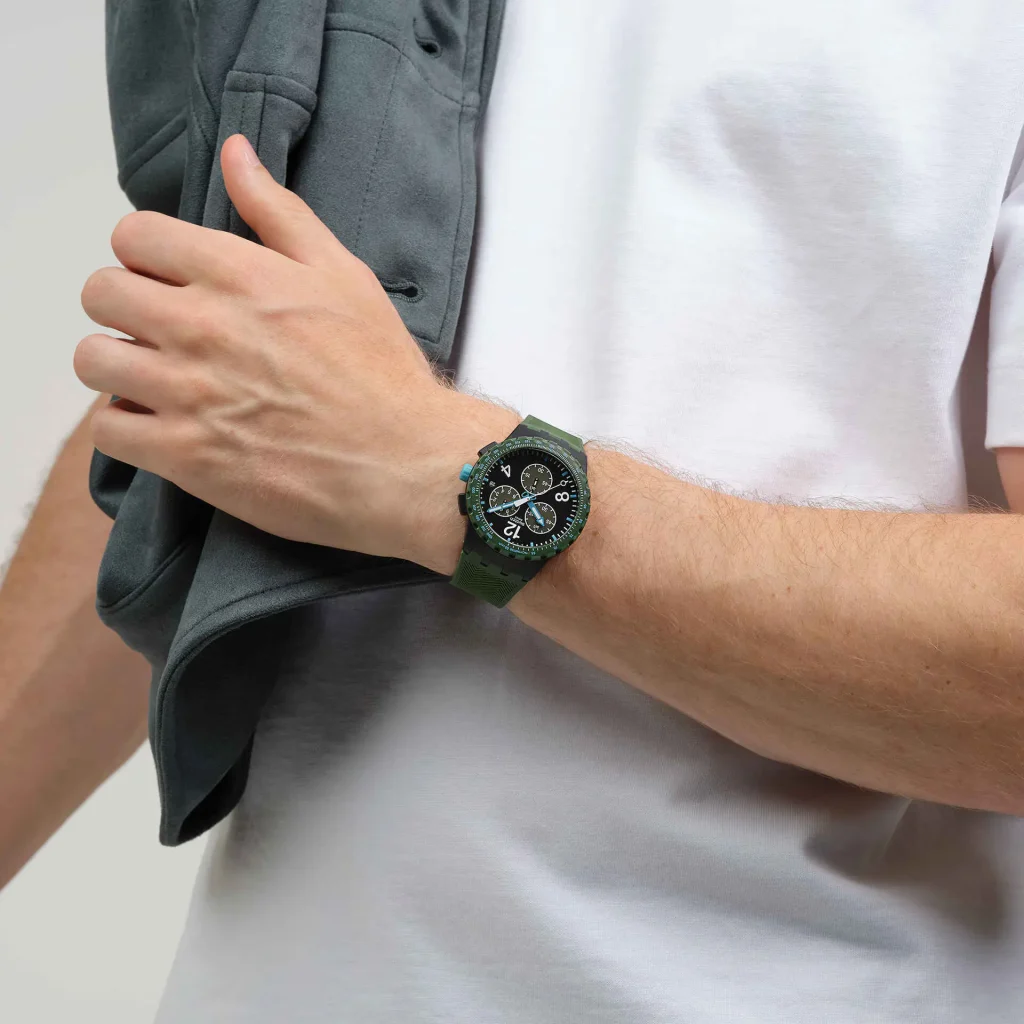 Relógio verde no pulso de homem com casaco.