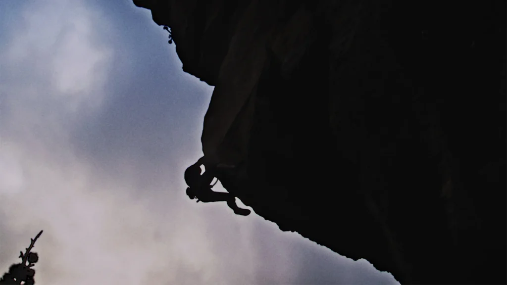 Silhueta de um escalador a desafiar a gravidade numa rocha íngreme em Tenerife durante o mapeamento de emoções fortes para a nova rota turística