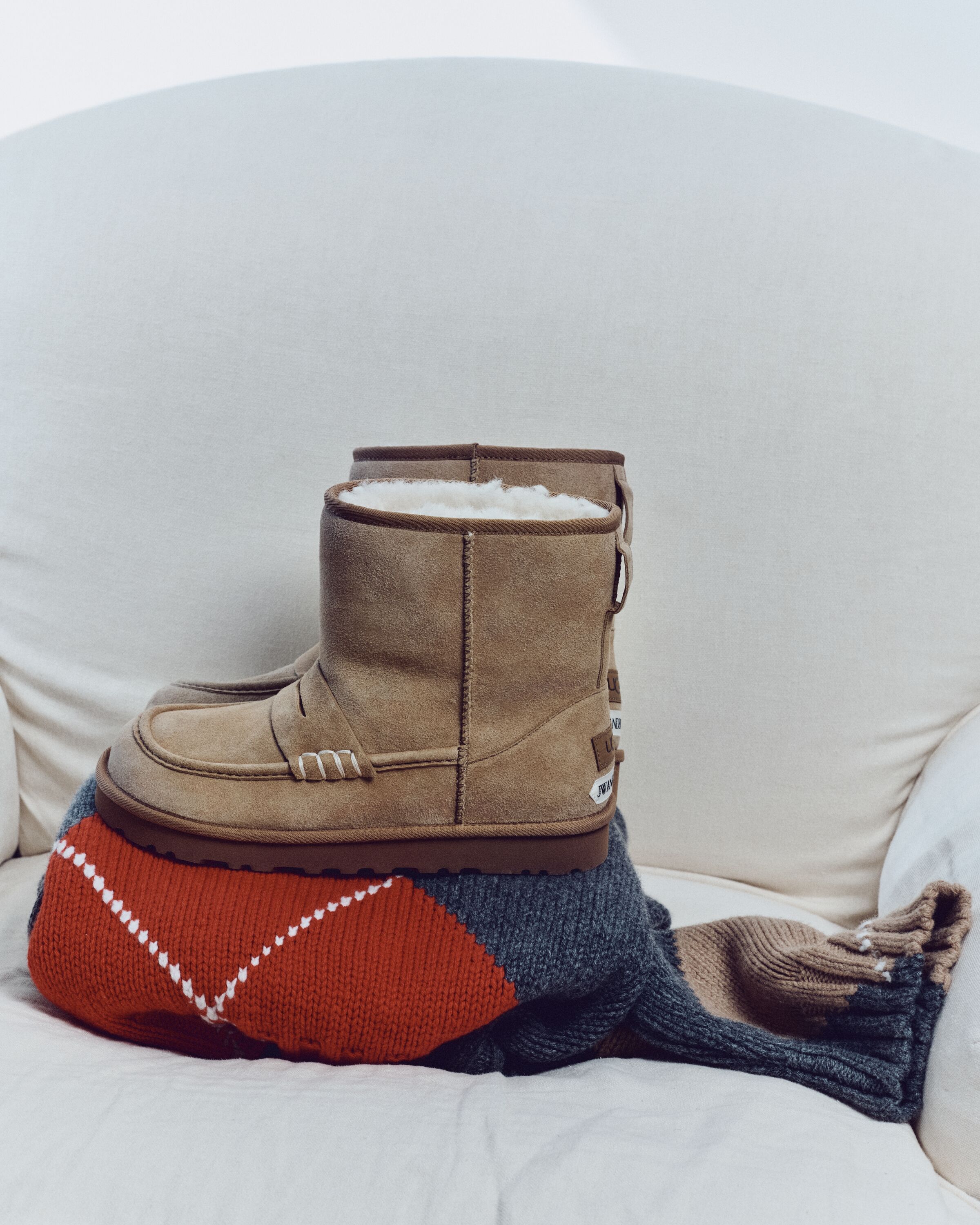 Botas UGG JW Anderson Loafer Boot em camurça castanha com interior em pelo branco sobre uma camisola de malha
