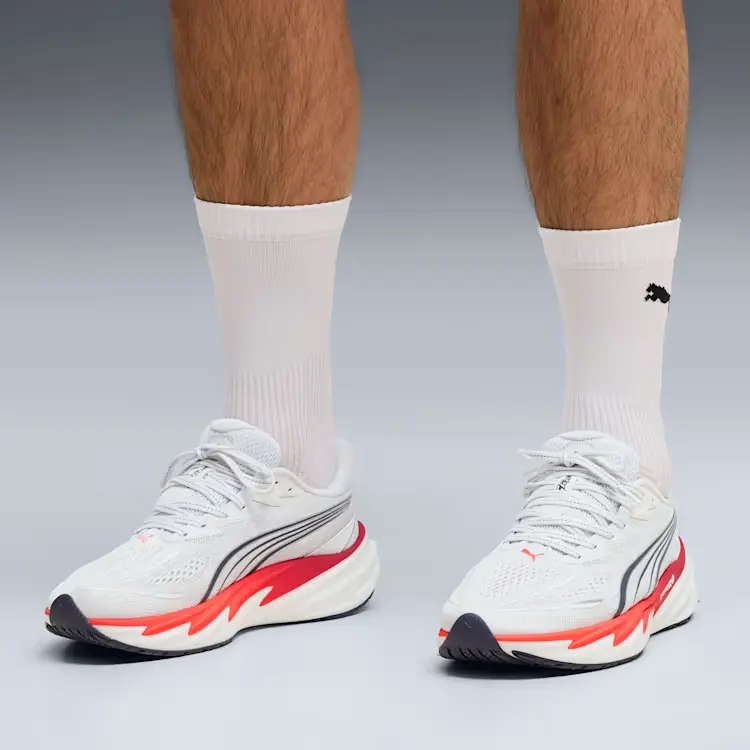 Pessoa a usar ténis de corrida Puma brancos e meias.