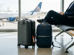Mala cinzenta e mochila azul num terminal de aeroporto.