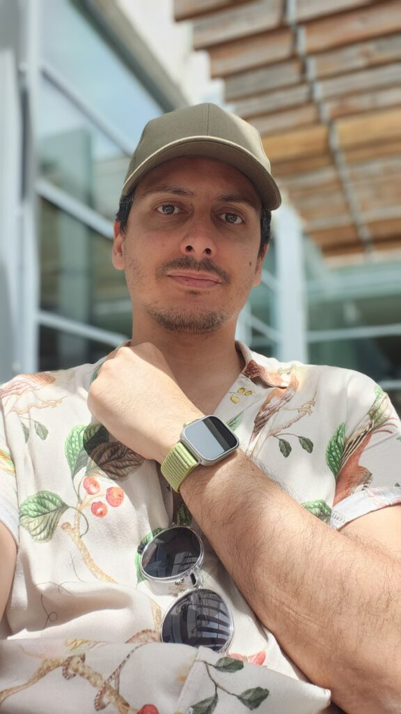 Pessoa com boné e relógio em ambiente externo.
