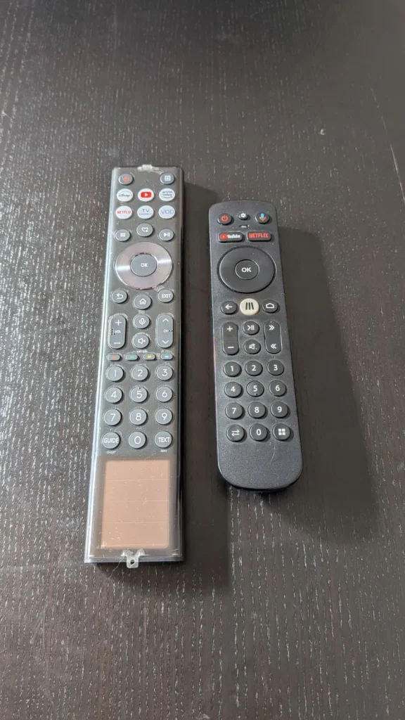 Dois comandos de TV em cima de uma mesa.