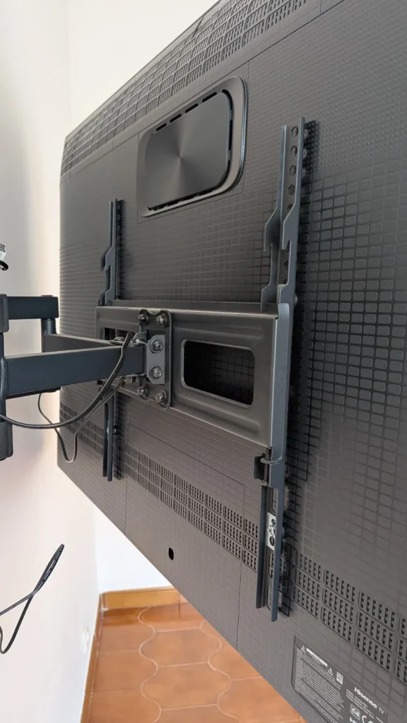 TV montada na parede com suporte articulado.