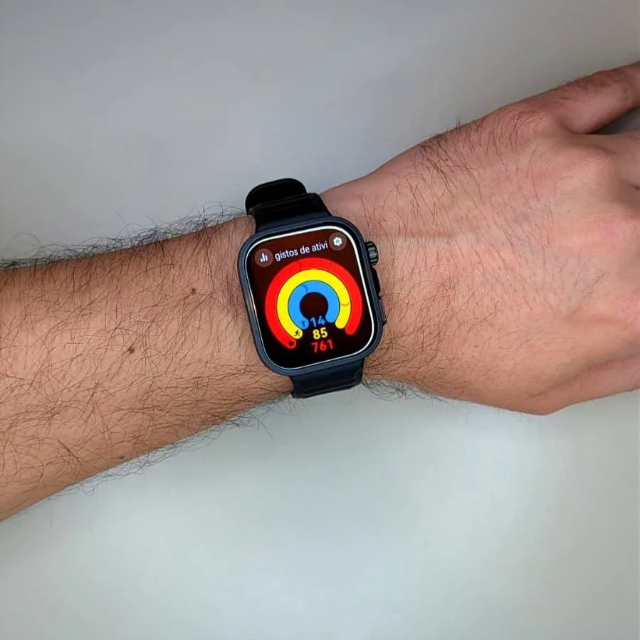 Smartwatch num pulso a exibir anéis de atividade física coloridos.
