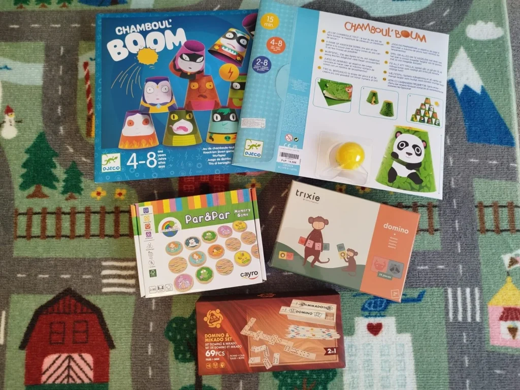 Quatro caixas de jogos de tabuleiro sobre um tapete infantil.