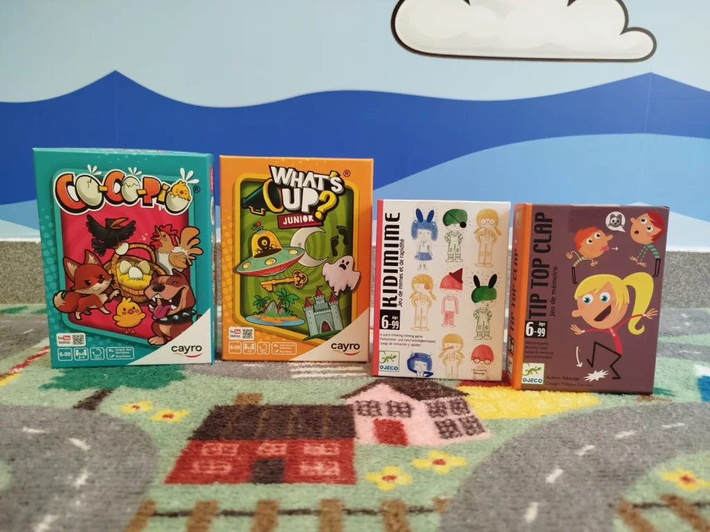 Quatro caixas de jogos de tabuleiro infantis sobre um tapete.