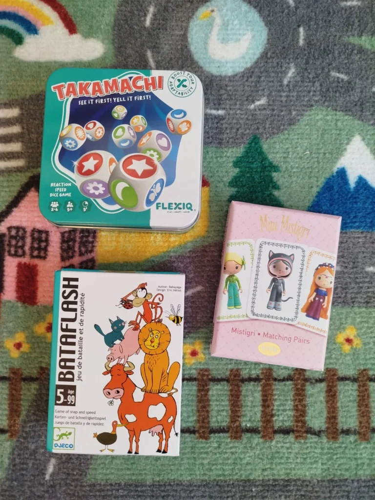 Três jogos de tabuleiro infantis sobre um tapete colorido.