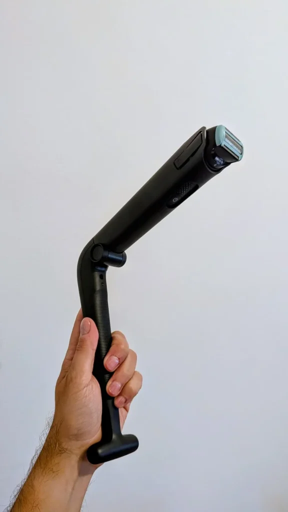 Mão a segurar uma máquina de depilação corporal articulada.