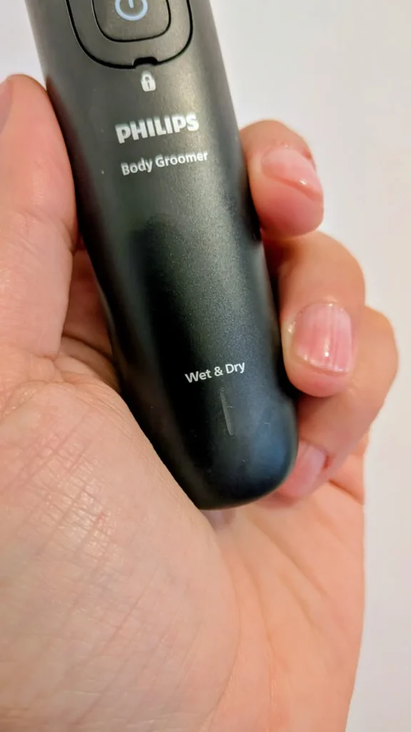 Mão a segurar uma máquina de depilação Philips Body Groomer.