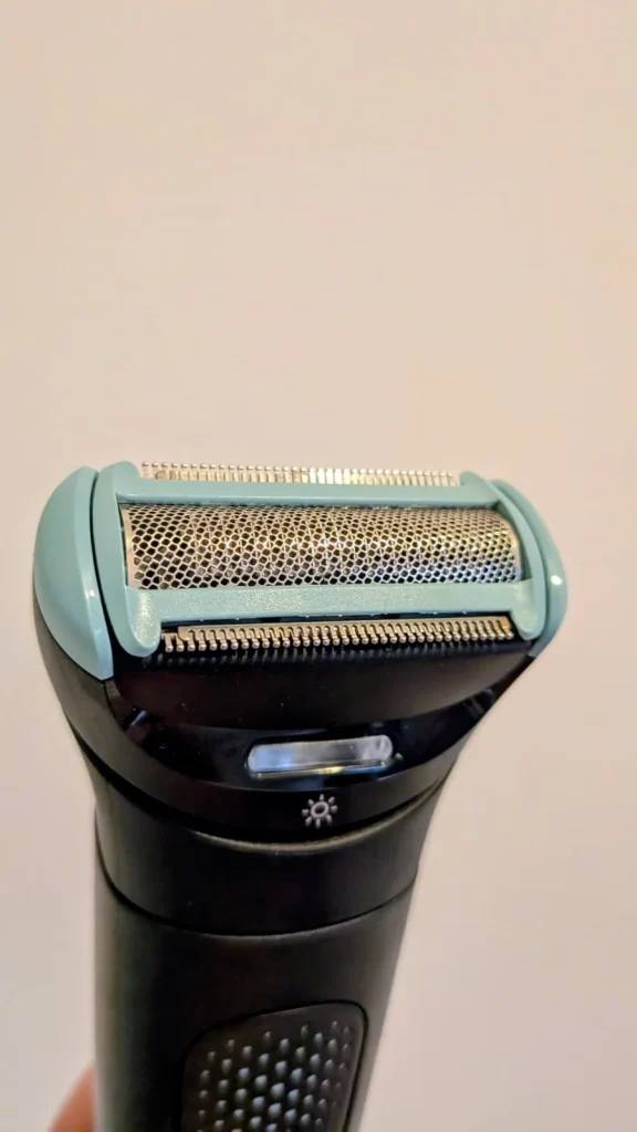 Close-up de cabeça de máquina de barbear elétrica azul e preta.