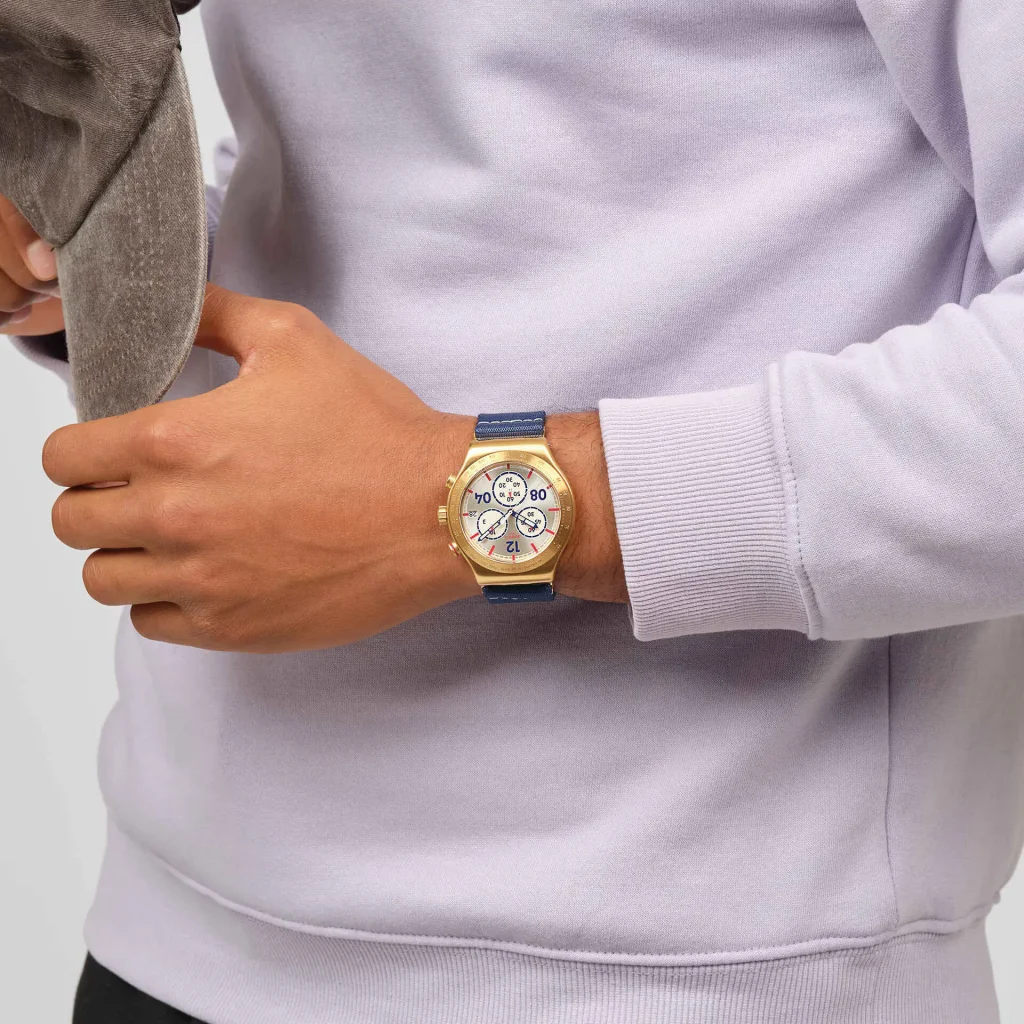 Homem com relógio dourado e azul no pulso.